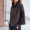 Model wearing NAYA placement print top with contrast cut-away collar (NAW25276), styled with black cargo trousers and a black cap, smiling in a studio setting.